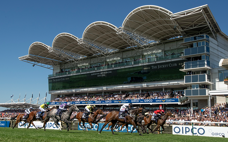 Racehorses galloping past a grandstand